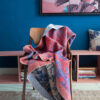 plaid op stoel met wandkleed op blauwe muur.